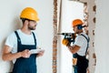 Focus of handyman holding digital tablet while coworker working in house Royalty Free Stock Photo