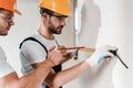 Focus of handymen in goggles measuring wall with measuring tape