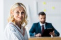 Focus of happy blonde employee near recruiter