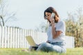 Focus of happy woman talking on smartphone and using laptop while sitting on grass Royalty Free Stock Photo