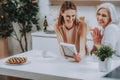 Happy daughter with mother are admiring photo in kitchen Royalty Free Stock Photo