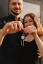 Focus on keys, held by excited young spouses homeowners. Happy married family couple celebrating moving in new house home , Royalty Free Stock Photo