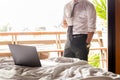 Focus laptop on the bed with businessman holding coffee in cup in background.