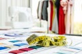 Focus on measuring tape and stack of colorful fabrics on dressmaker`s desk, Tailoring accessories, Fashioner market concept