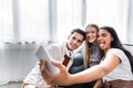 Focus of multicultural friends smiling and taking selfie in apartment Royalty Free Stock Photo