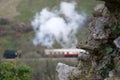 Focus on old stone wall; traditional steam train and carriages in background Royalty Free Stock Photo