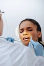 Focus of orthodontist in latex gloves holding dental instruments near upset african american woman in braces Royalty Free Stock Photo