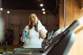 Focus overweight girl wiping neck with towel while holding sports bottle