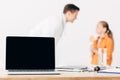 Focus of pediatrist and child and laptop with blank screen on foreground Royalty Free Stock Photo