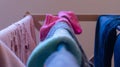 Focus on a pink sock drying on a laundry rack with other woman`s clothes, and mismatched socks blurred in the foreground.