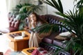 Focus on plant.Weekend Pastime. Young Woman Relaxing In Armchair With Tv controller Enjoying Spending Time At Home home trees