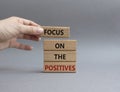 Focus on the Positives symbol. Concept word Focus on the Positives on wooden blocks. Beautiful grey background. Businessman hand. Royalty Free Stock Photo