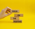 Focus on the Positives symbol. Concept word Focus on the Positives on wooden blocks. Beautiful yellow background. Businessman hand Royalty Free Stock Photo