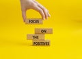 Focus on the Positives symbol. Concept word Focus on the Positives on wooden blocks. Beautiful yellow background. Businessman hand Royalty Free Stock Photo