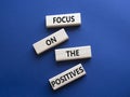 Focus on the Positives symbol. Concept words Focus on the Positives on wooden blocks. Beautiful deep blue background. Business