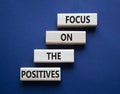 Focus on the Positives symbol. Concept words Focus on the Positives on wooden blocks. Beautiful deep blue background. Business