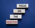 Focus on the Positives symbol. Concept words Focus on the Positives on wooden blocks. Beautiful deep blue background. Business