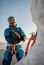 Focus on professional ice axe. Man climber with equipment and ropes on the slope at background Royalty Free Stock Photo