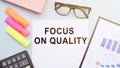 Focus on Quality words on notebook. Product or service quality concept in business