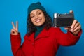 Focus on retro style photographic equipment vintage camera in the hands of blurred pretty woman, showing peace sign and smiling