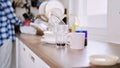 Focus shot of a pile dirty dishes on a kitchen counter with a person standing in the background.