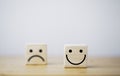 Focus of Smile face and defocus of sad face on wooden block cube for positive mindset selection concept Royalty Free Stock Photo