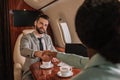 Focus of smiling businessman shaking hands with african american businesswoman in plane Royalty Free Stock Photo