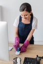 Focus of smiling cleaner holding rag while cleaning computer mouse on office table Royalty Free Stock Photo