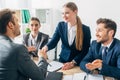 Focus of smiling recruiter shaking hands with employee near colleagues clapping at table