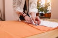 Focus on tailor`s hands using soap transfers sewing pattern on orange colored satin fabric in a fashion design studio. Tailoring Royalty Free Stock Photo