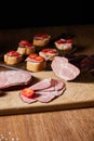 Focus of tasty ham slices, cherry tomatoes on cutting board near canape