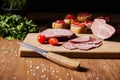 Focus of tasty ham slices, cherry tomatoes and knife on cutting board near parsley and canape