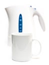 Focus on a tea mug. Electric tea kettle on a white background and a mug