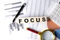 FOCUS text on wooden block on graph background with pen and magnifier Royalty Free Stock Photo