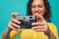 Focus on a vintage camera- old retro style photographic equipment in the hands of a blurred smiling cheerful woman with curly hair