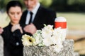 Focus of white flowers and mortuary urn near man and woman in graveyard Royalty Free Stock Photo