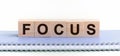 FOCUS - a word made of wooden blocks with black letters, a row of blocks is located on a blue Notepad