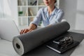 Focus of young businesswoman working on laptop at workplace with yoga mat, notepad, smartphone and eyeglasses