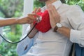 Focus young man hand holding the red heart on the left chest, with the doctor`s headphones held by the girl attached Royalty Free Stock Photo
