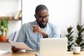 Focused african american businessman working with laptop documents in office