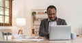 Focused african american businessman working with laptop documents in office holding papers preparing report analyzing Royalty Free Stock Photo