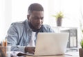 Focused african american employee working on laptop in office