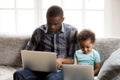 Focused African American family using laptops together at home