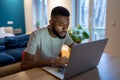 Focused African American guy freelancer working on laptop at home office, feeling overwhelmed Royalty Free Stock Photo