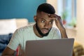 Focused African American guy freelancer working on laptop at home office, feeling overwhelmed Royalty Free Stock Photo