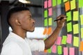 African American male employee brainstorm writing ideas on notes