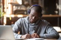 Concentrated black male student in Bluetooth headphones studying Royalty Free Stock Photo