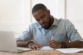 Focused african American male studying at laptop making notes Royalty Free Stock Photo