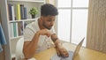 Focused african american man using laptop in a cozy home interior Royalty Free Stock Photo