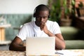 Focused African American man wear headphones, using laptop